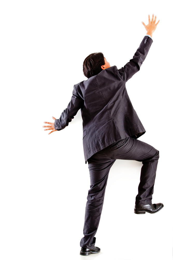 Businessman climbing a wall - isolated over a white background